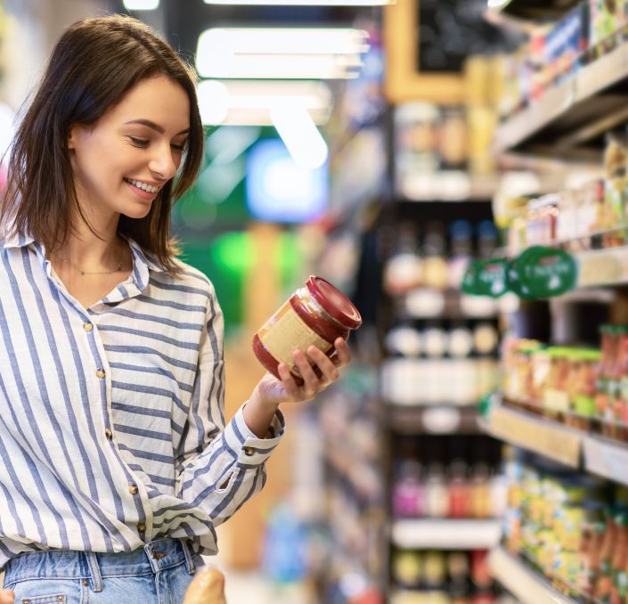 Auswahl eines Produktes im Supermarkt und Blick auf das Artikeletikett mit Nährwerten